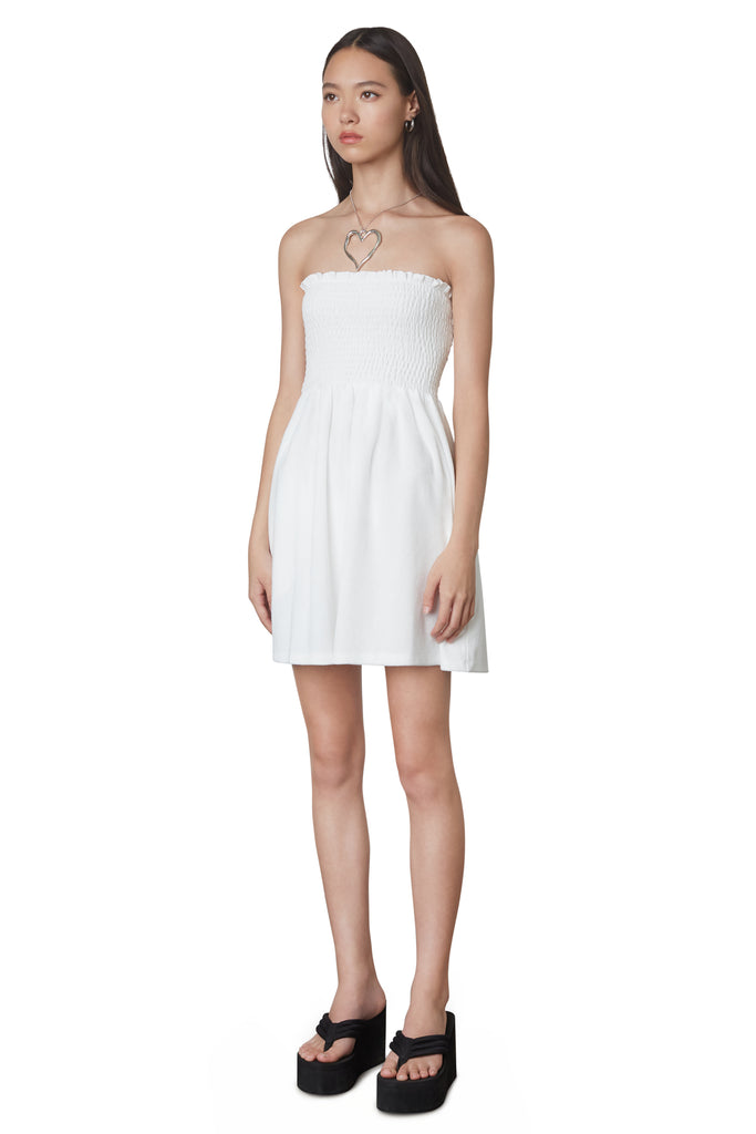 Smocked Terry Dress in White: Terrycloth mini strapless dress featuring a smocked bust and hidden pockets. Unlined. Side view.