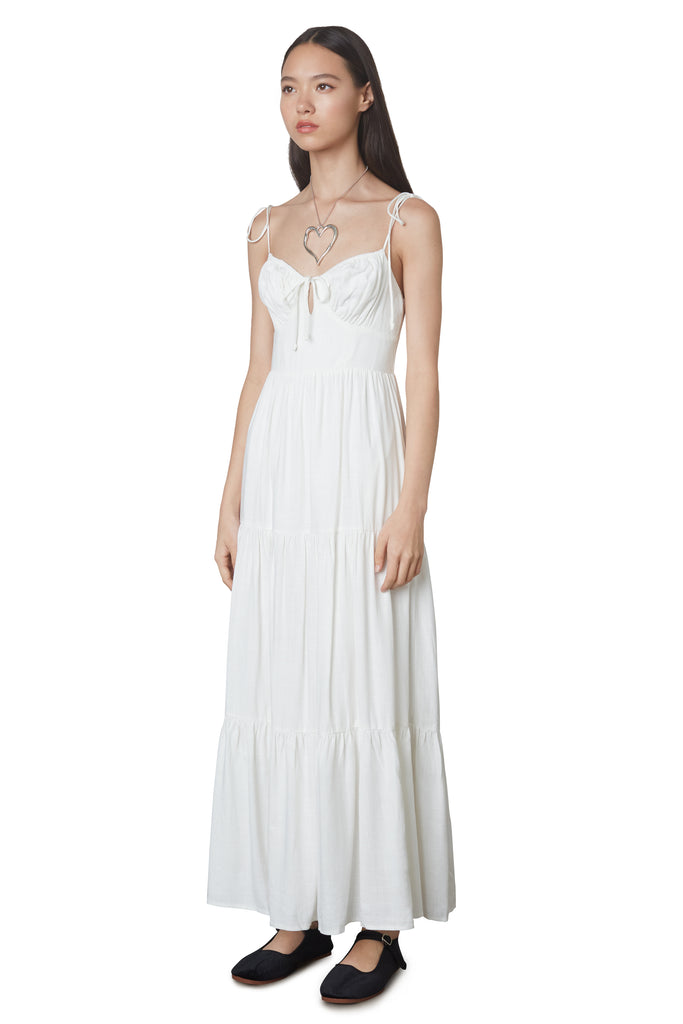 Aimee Dress in White: Linen blend maxi dress festering a tiered skirt, self tie straps, and back zipper closure. Side view