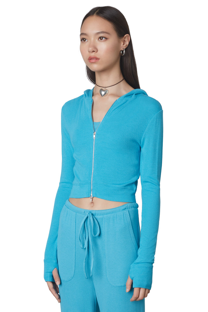 Cropped Hacci Hoodie in Capri: Form fitting cropped ribbed zip up hoodie with double zipper detail and thumb holes. Side view.